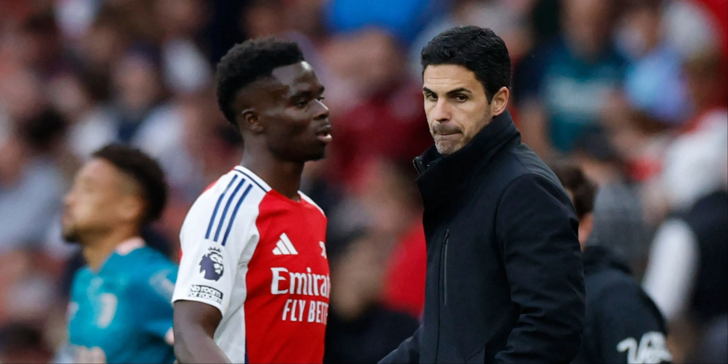 HLV Mikel Arteta trao đổi với Bukayo Saka trên sân cỏ.