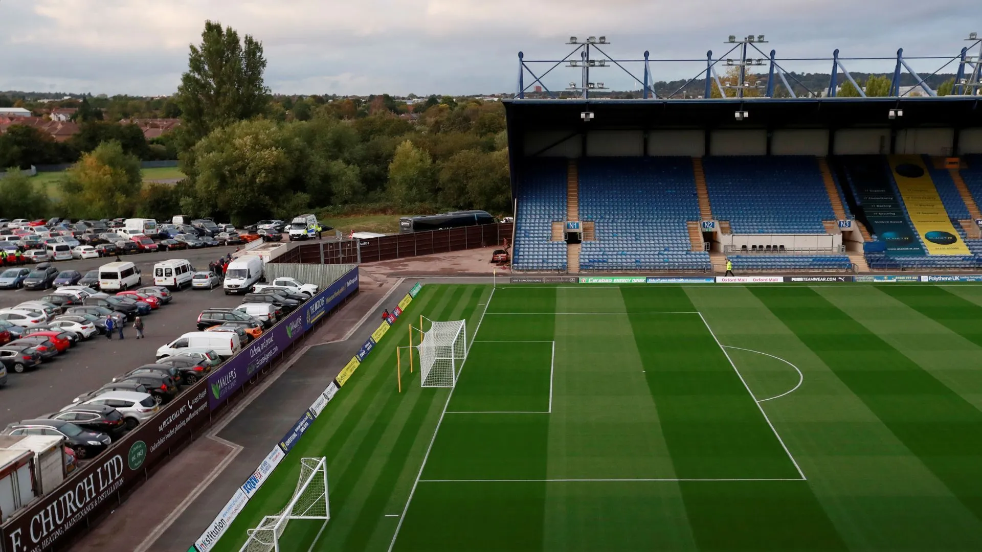 Sân Kassam Stadium, sân nhà của Oxford United, với mẫu áo đấu vàng - xanh navy 2025/26.